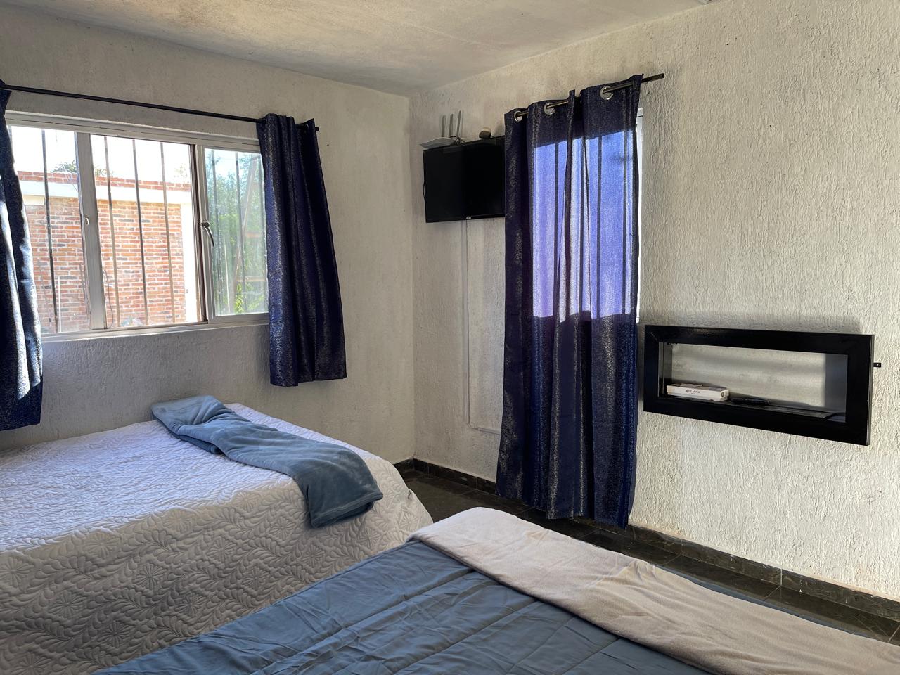 Recámara con cortinas azules y televisión